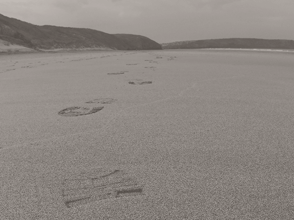 Footprints in snow on a frozen lake with distant hills under an overcast sky