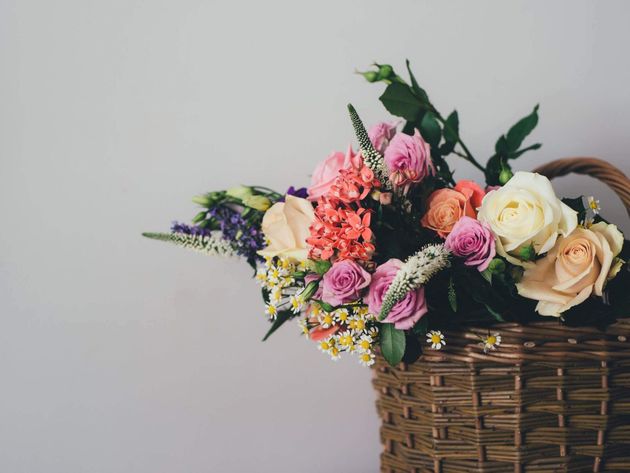 Mixed bouquet of pink, cream, and purple flowers in a wicker basket