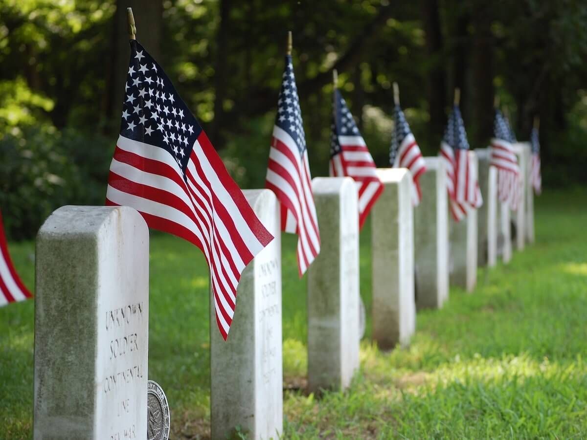 American flags placed beside white gravestones in a cemetery.