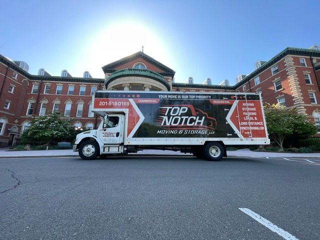 Top Notch moving truck parked in front of a brick building on a sunny day