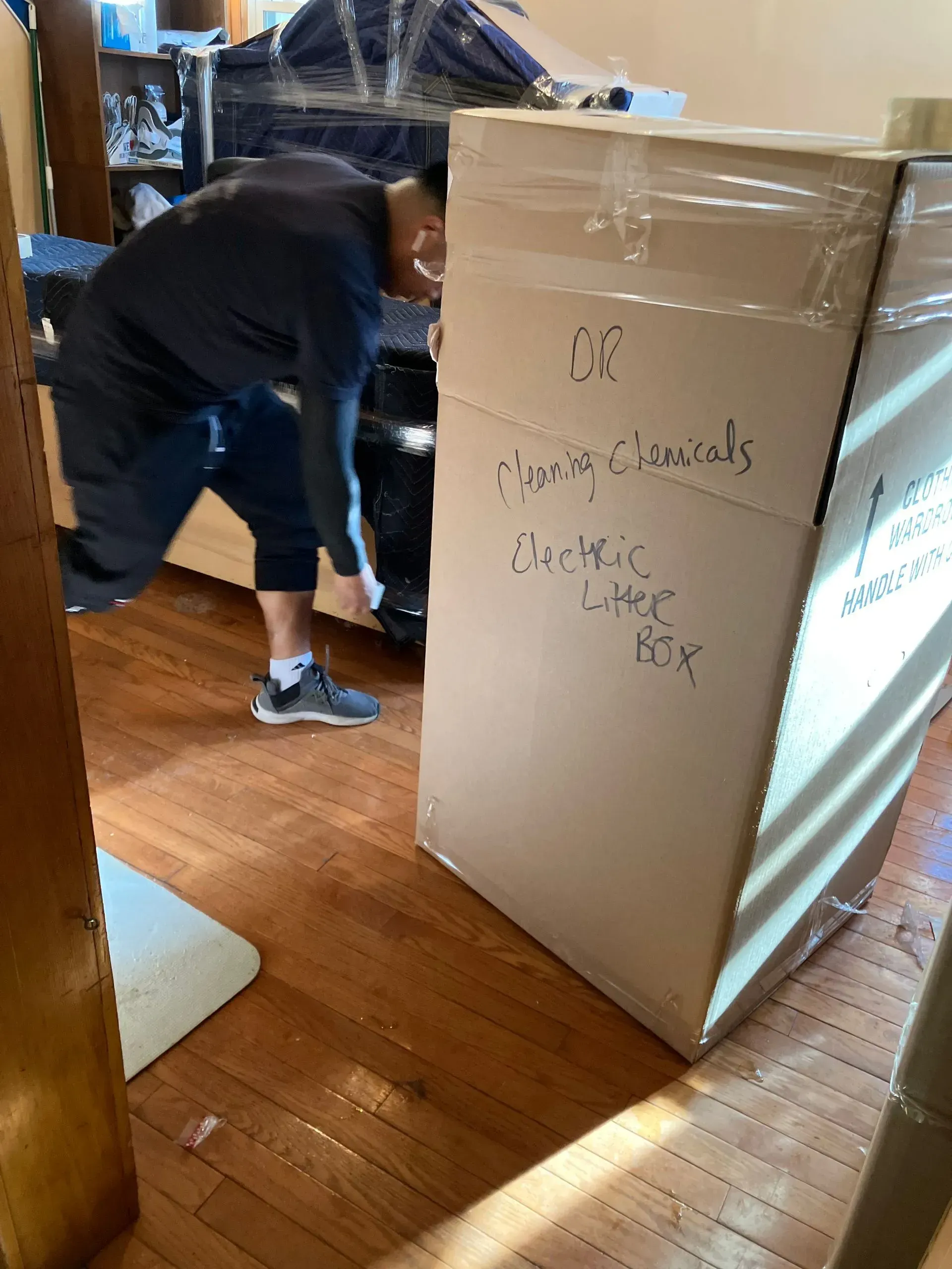 Person bending near a large cardboard box labeled 