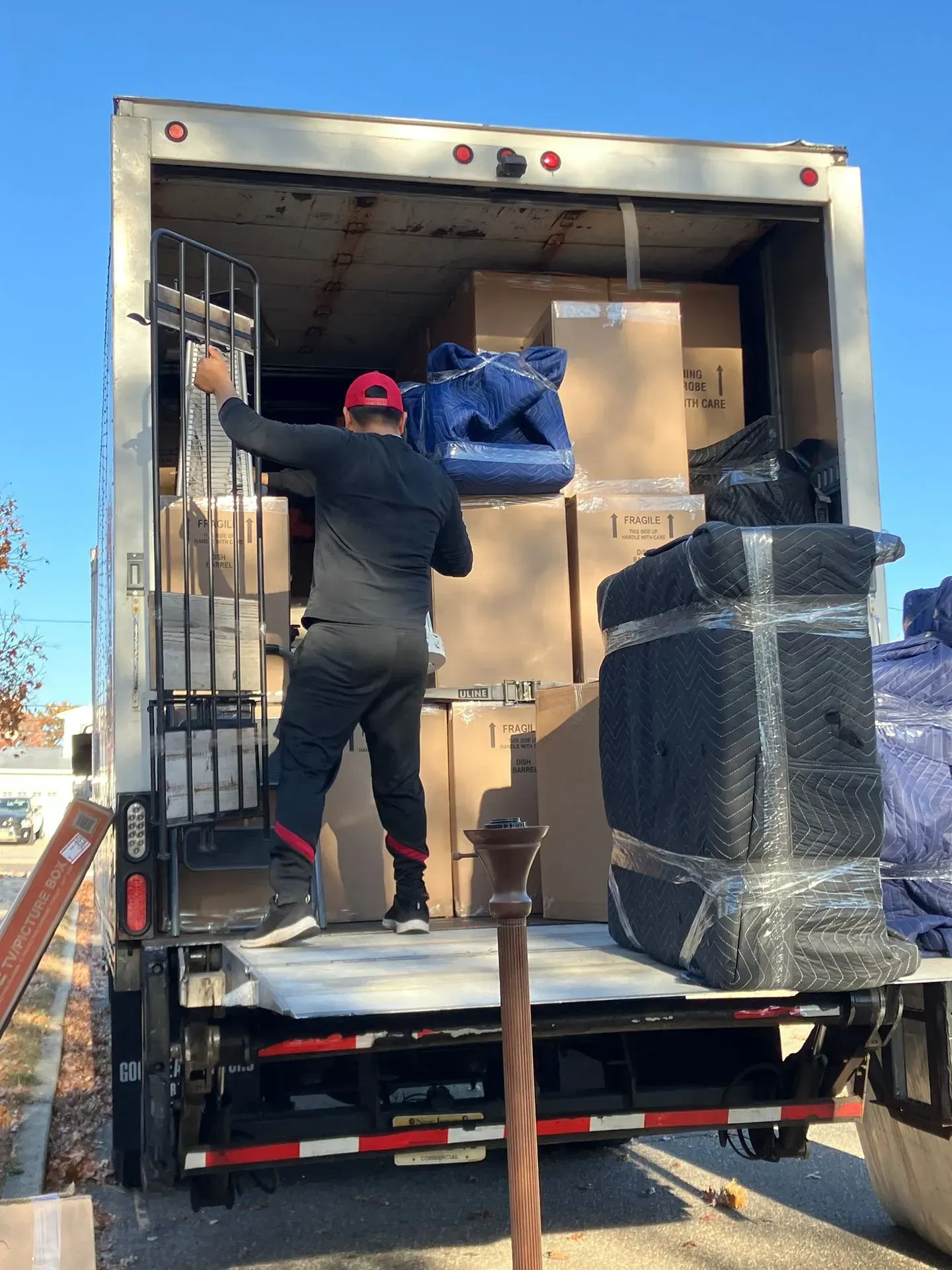 Person loading boxes into a moving truck. Exterior setting, daytime.