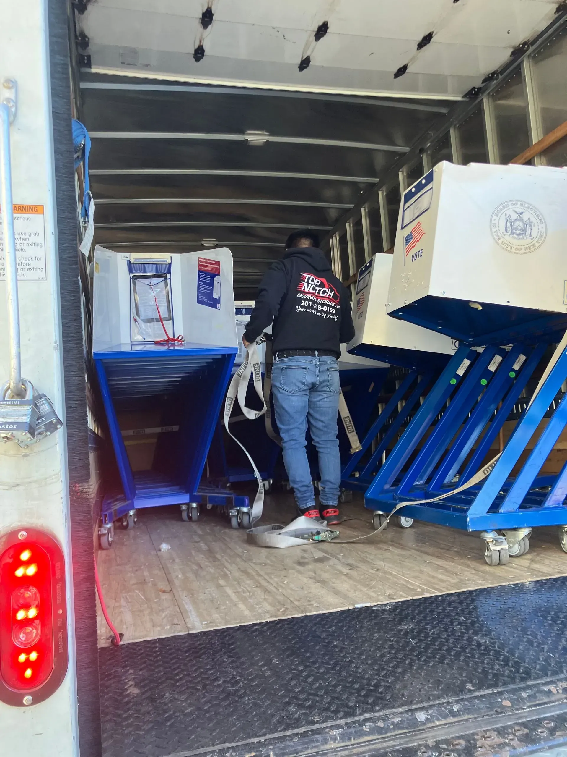A person loads white and blue equipment onto a truck. The truck's door is open.