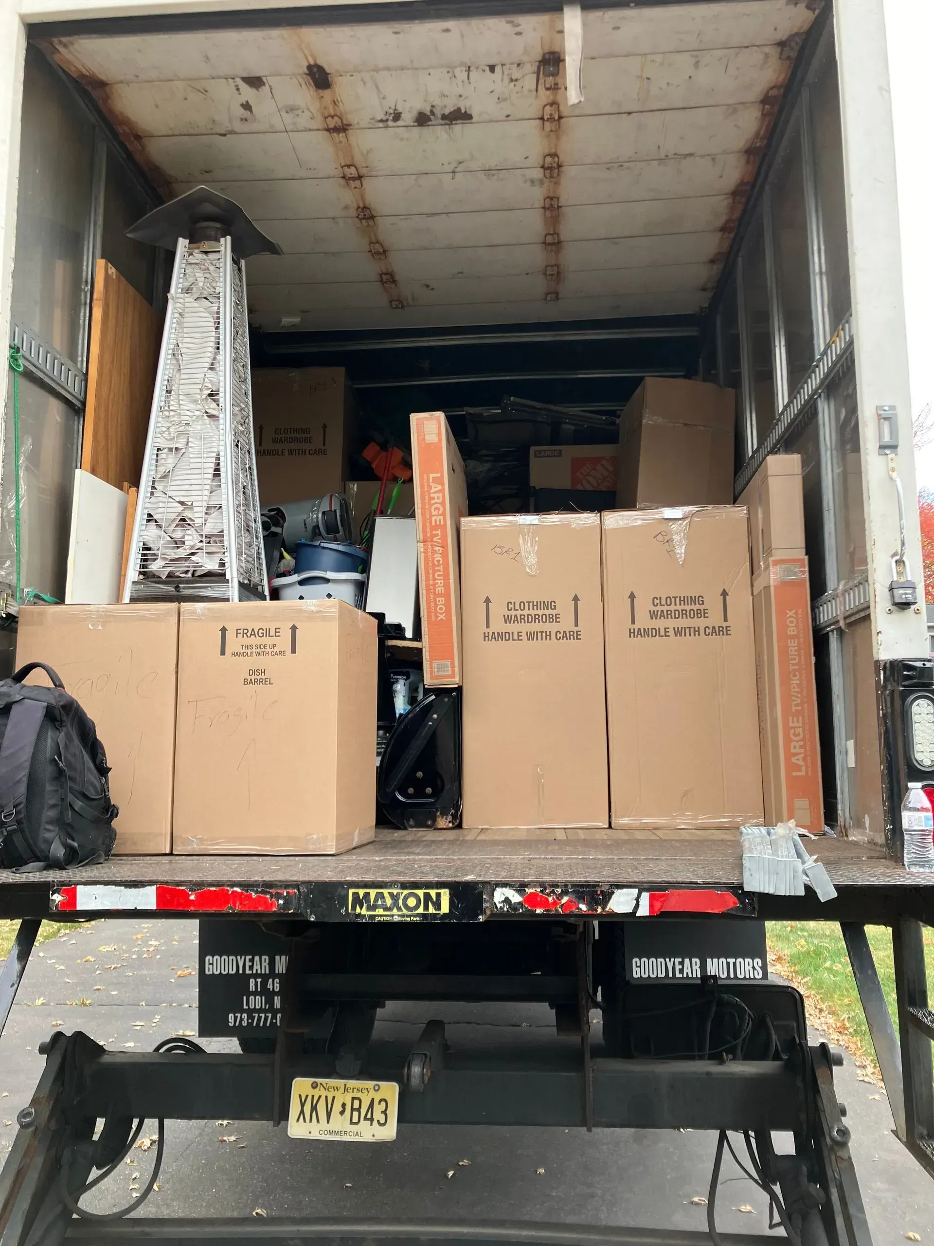 Back of a moving truck filled with cardboard boxes, furniture, and other household items.