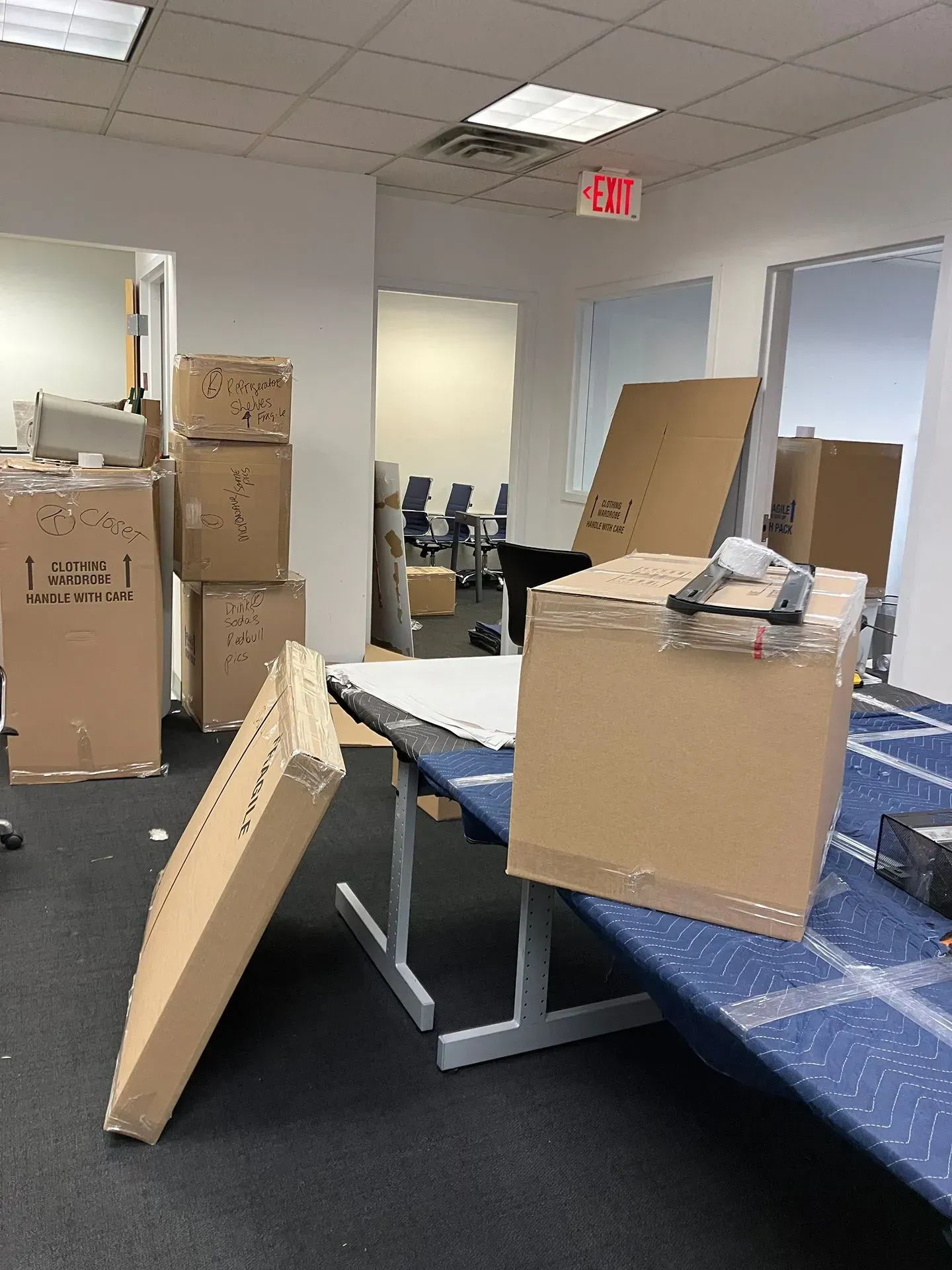 Office space filled with cardboard boxes and furniture, indicating a move or re-organization.