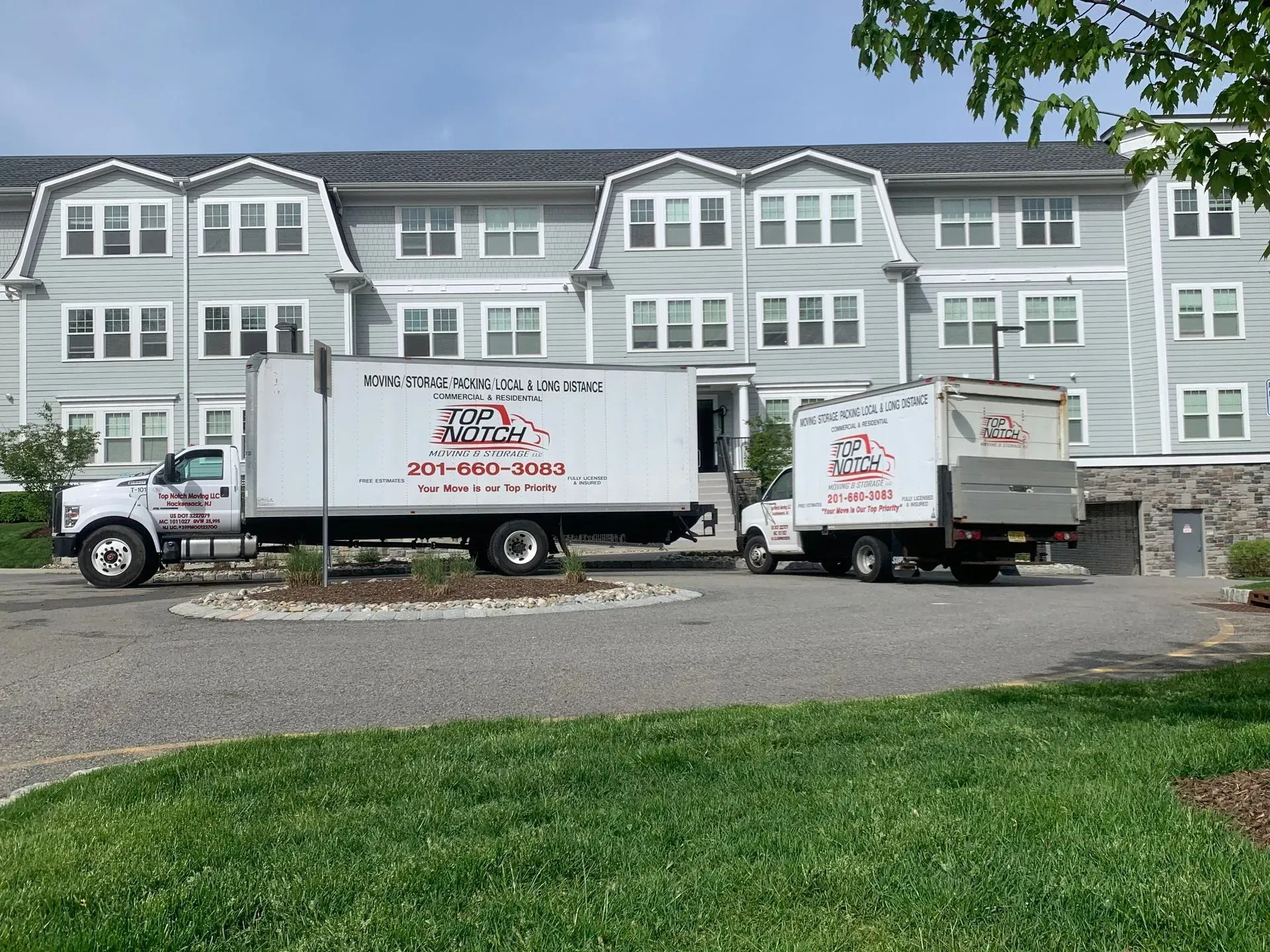 Moving trucks parked in front of a multi-story apartment building.