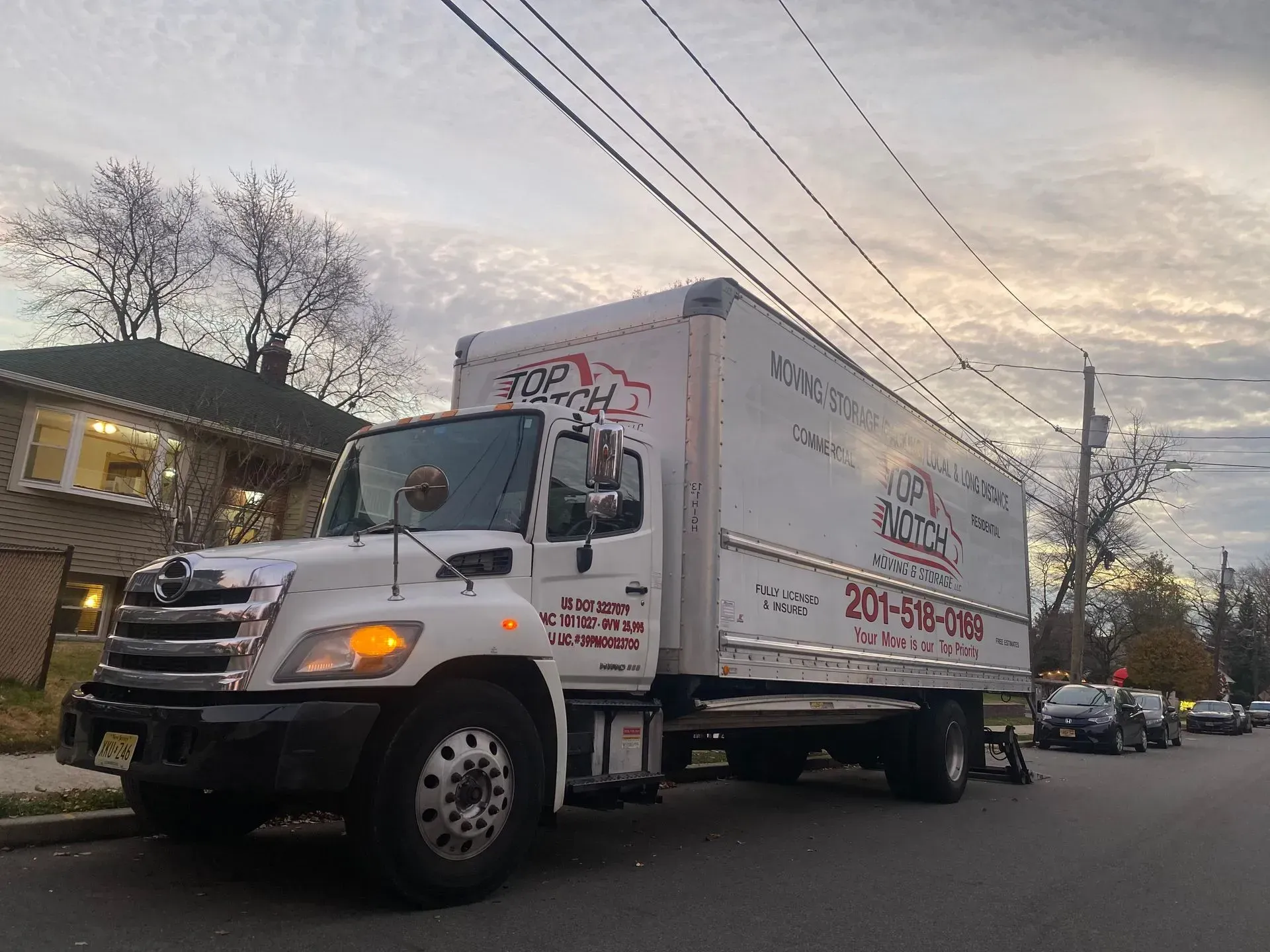 White moving truck parked on a residential street; cloudy sky.
