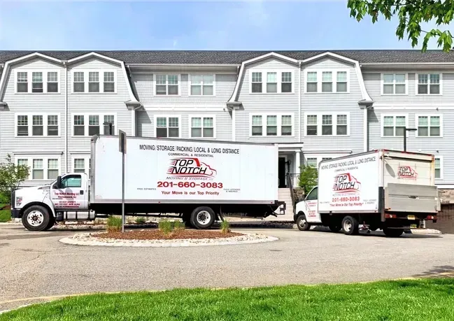 Two moving trucks parked outside a multi-story building. One truck is loading.