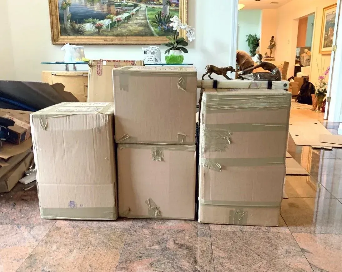 Boxes stacked inside a home, ready for moving. Brown cardboard boxes taped and prepared for relocation.