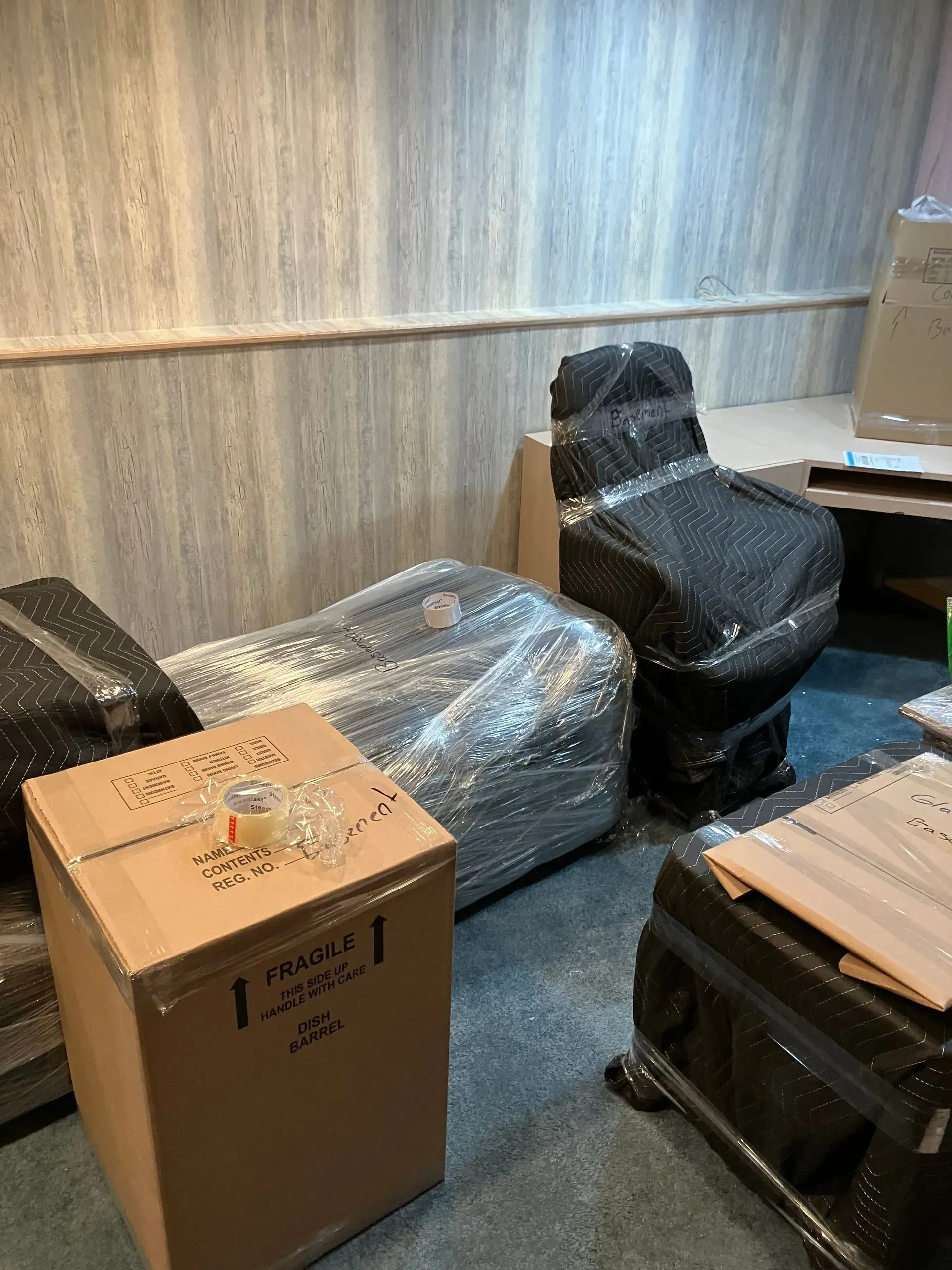 Boxes and furniture wrapped in plastic in a room, ready to move.