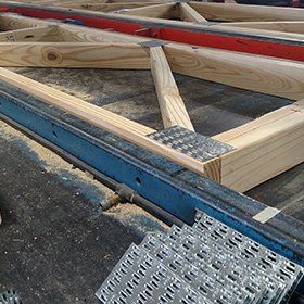 Wooden roof trusses with blue metal bracing, under construction.