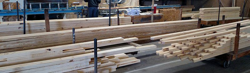 Wooden beams stored in a warehouse; a person is visible in the background.