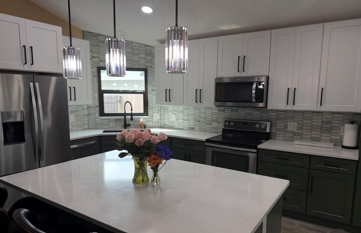 Modern kitchen with white island, stainless steel appliances, pendant lights, and a flower centerpiece
