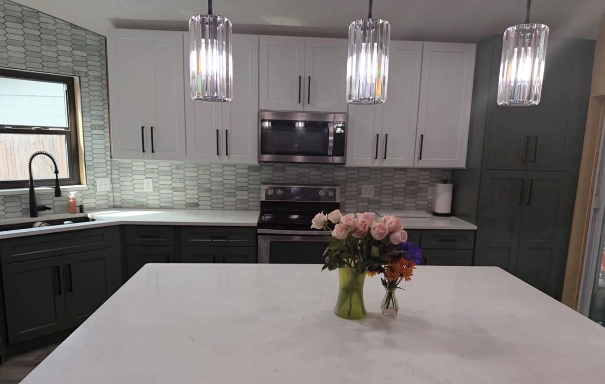 Modern kitchen with white island, dark cabinets, pendant lights, and a vase of flowers on the counter