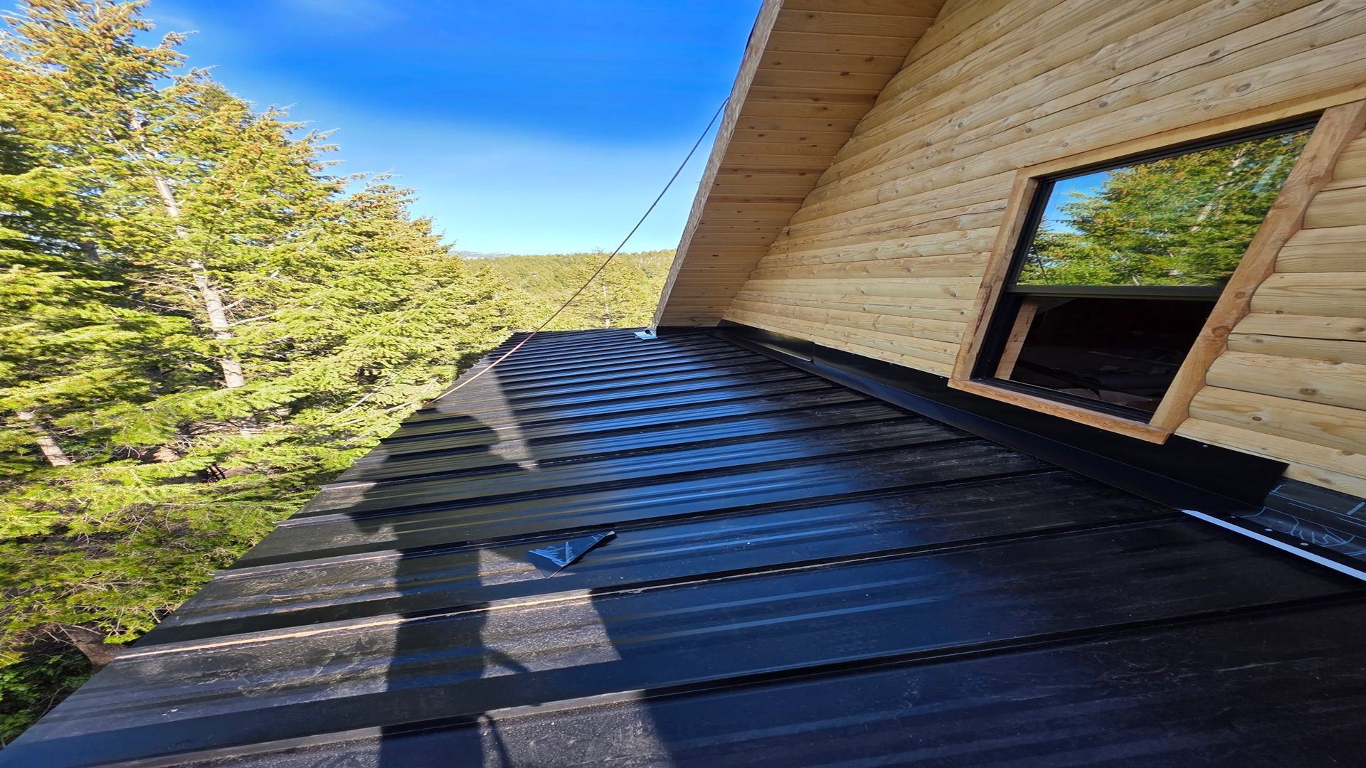 A wooden house with a black roof and a window.