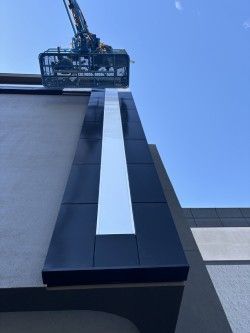 A crane is lifting a sign on the side of a building.