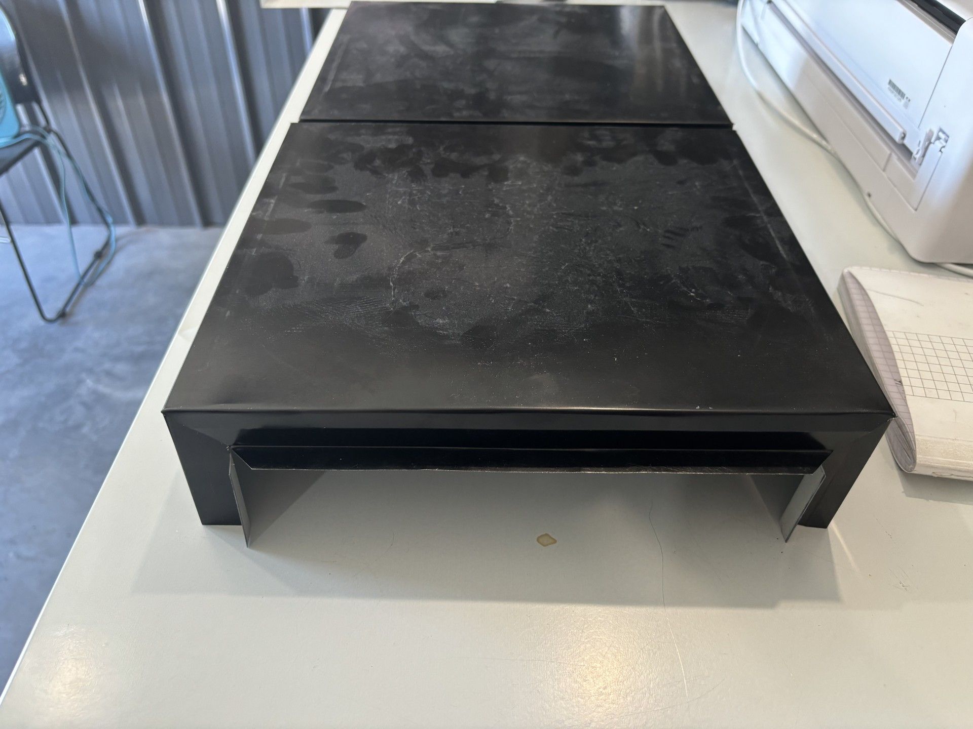 A black box is sitting on a white table next to a printer