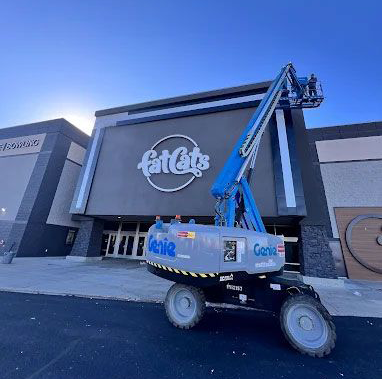 A genie lift is parked in front of a large building.