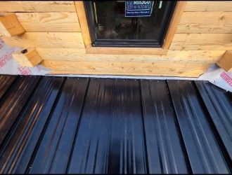 A wooden building with a black metal roof and a window.