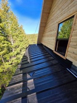 A wooden house with a black metal roof and a window.