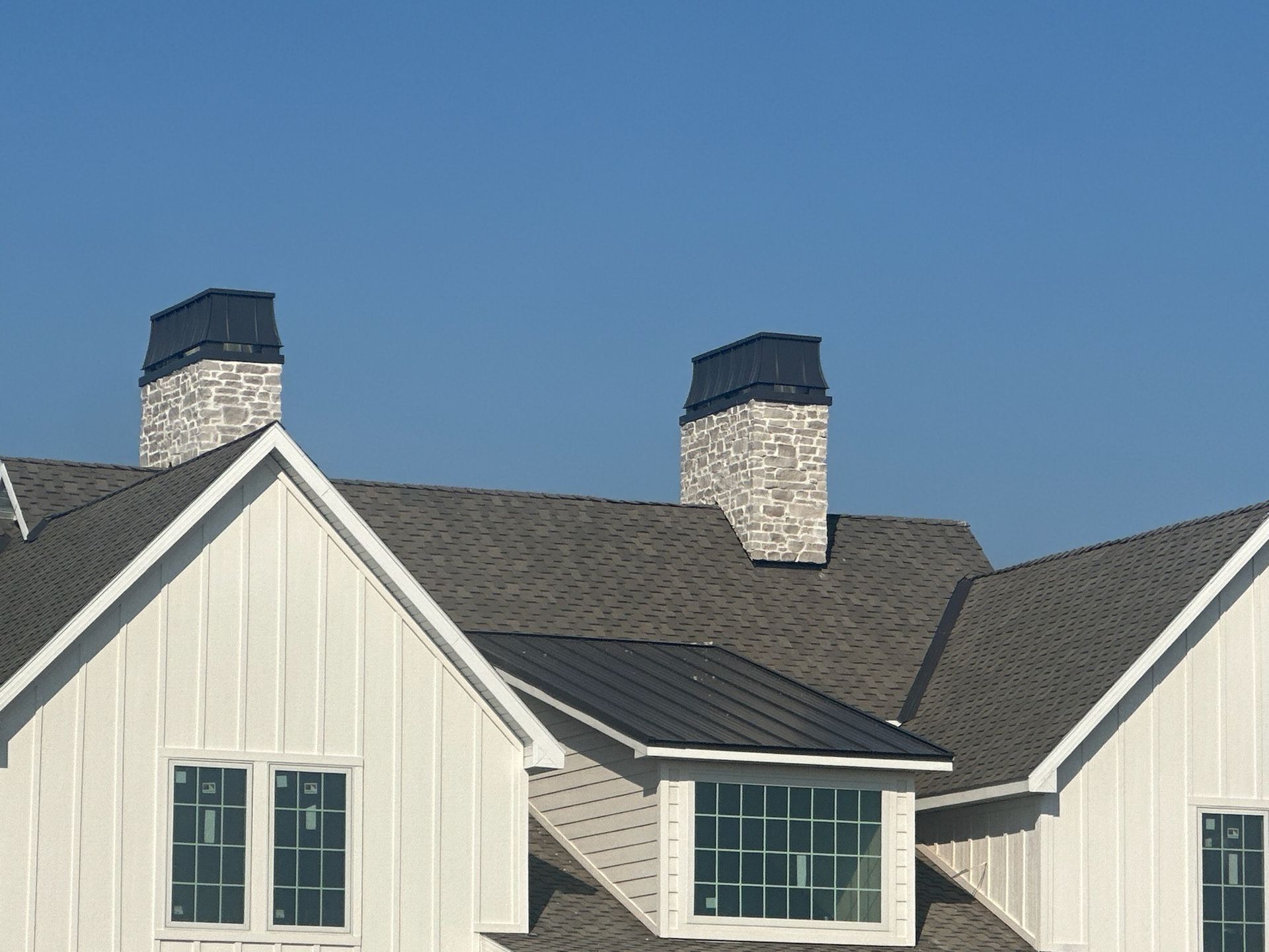 A white house with a black roof and chimneys