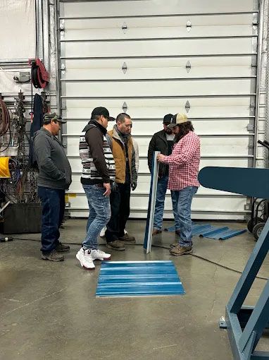 A group of people are standing around a piece of metal in a garage.