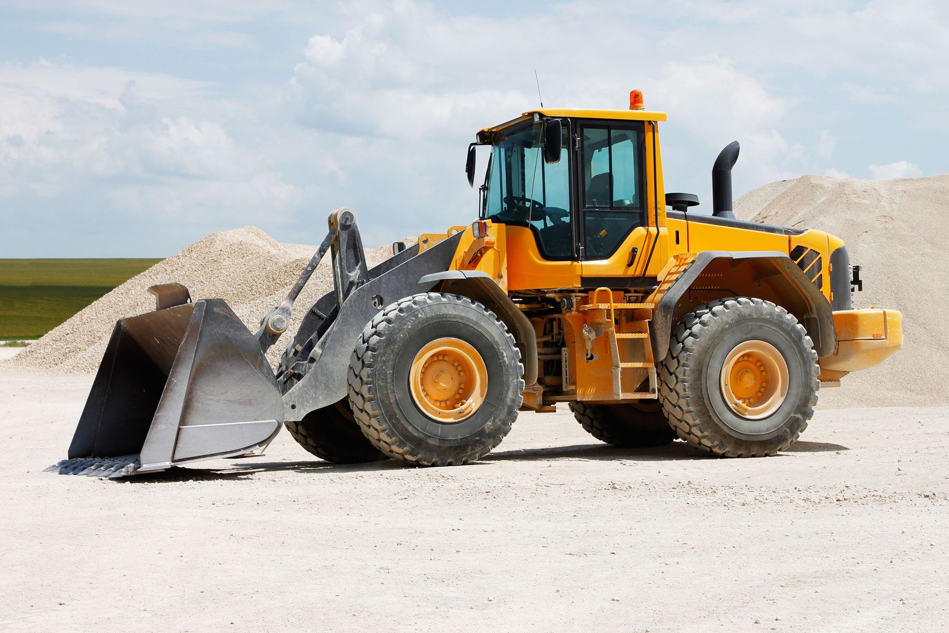 A yellow bulldozer is parked in front of a pile of dirt.