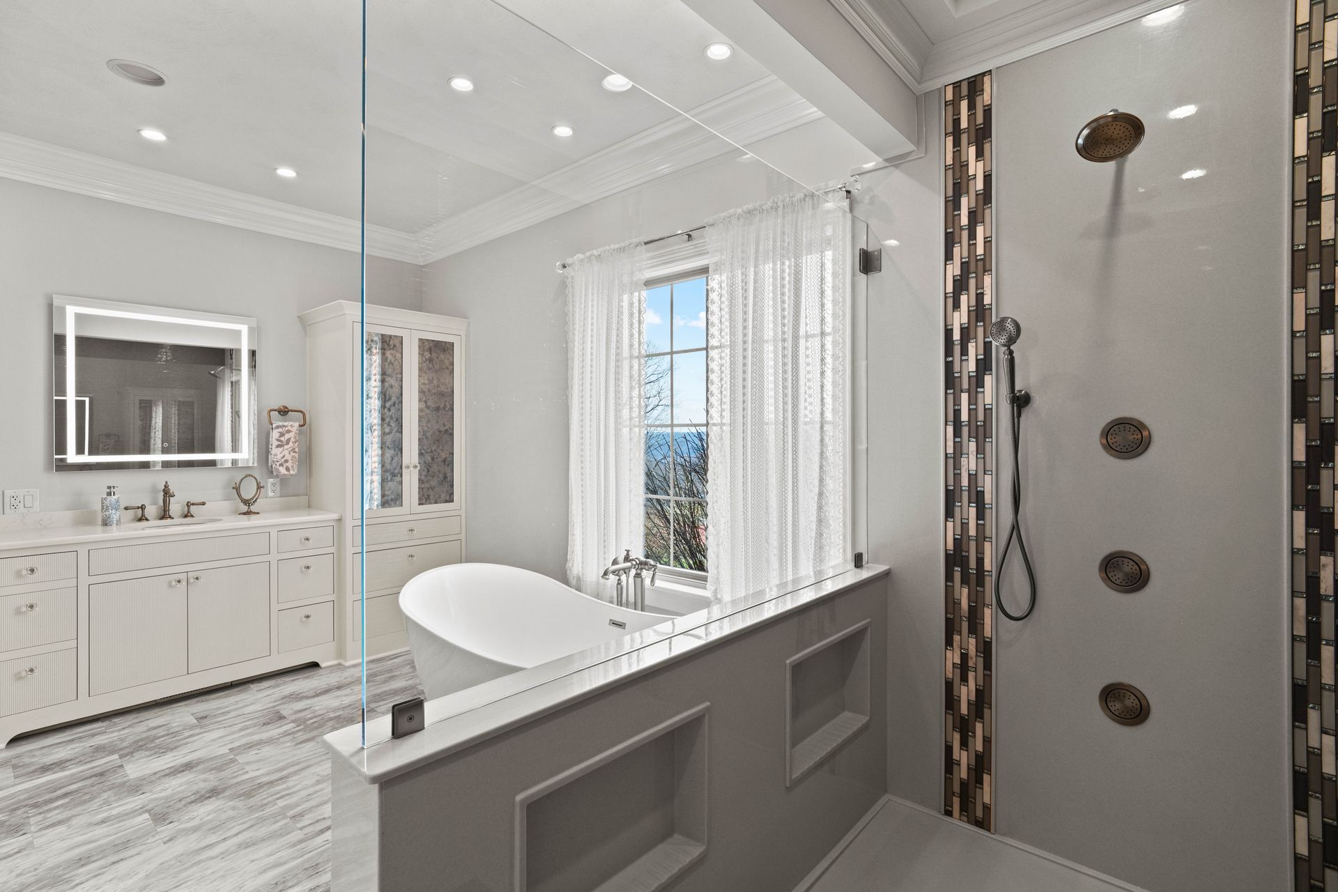 Bright modern bathroom with freestanding tub, double vanity, and glass shower doors