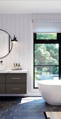 Modern bathroom with hex tile floor, patterned wallpaper, dark vanity, round mirror, and freestanding tub by a window