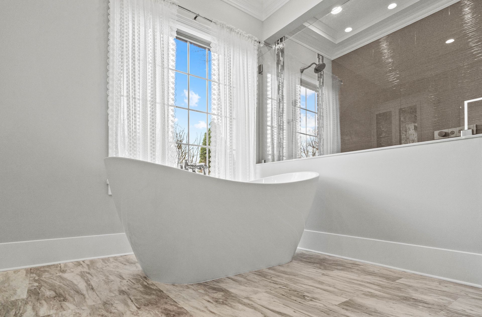 Bright modern bathroom with white trim, large window, and tiled shower area