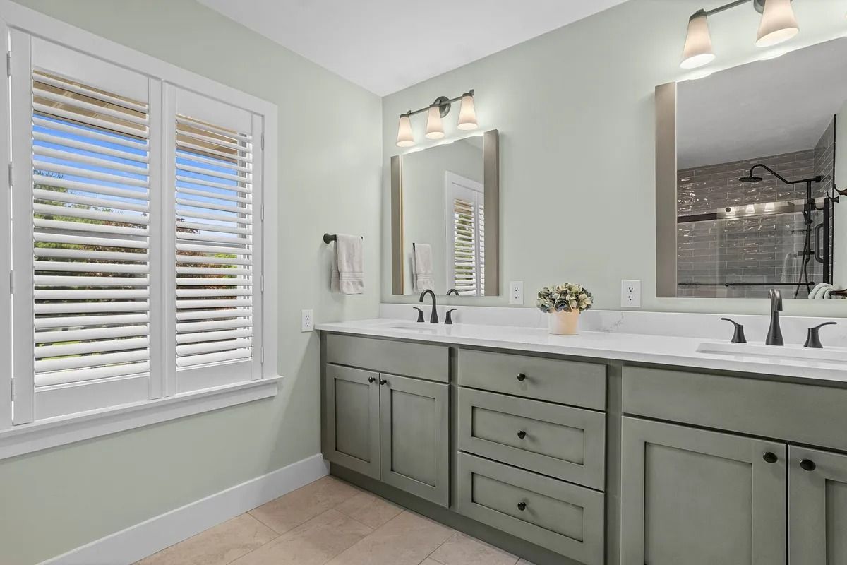 Bright bathroom with mint green vanity, white countertop, mirror, and window blinds.