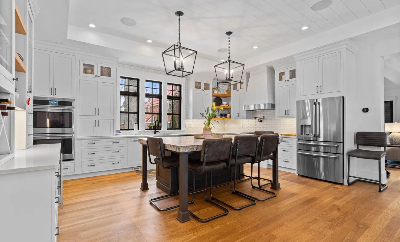Bright modern kitchen with white cabinets, stainless steel appliances, and a dark island with bar stools