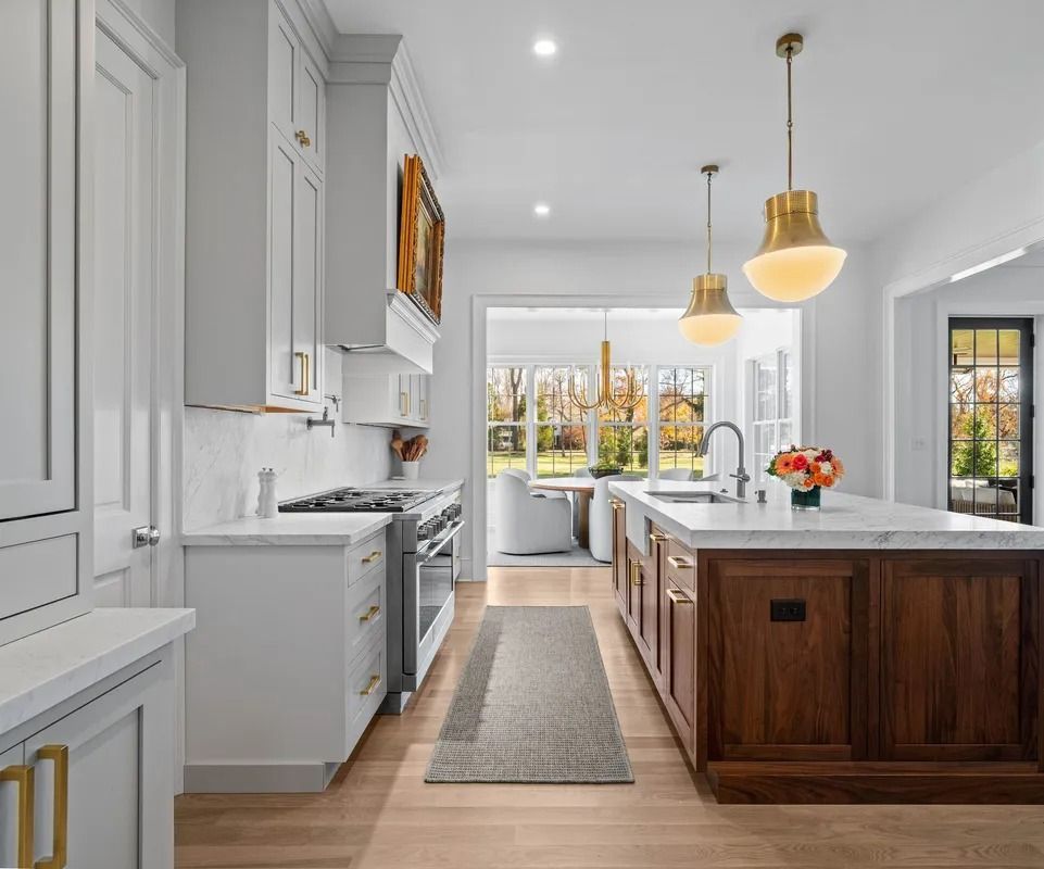 Bright modern kitchen with white cabinets, wood island, pendant lights, and a view to the backyard
