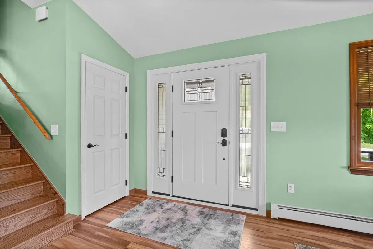 Mint green entryway with white front door, staircase, and wood flooring