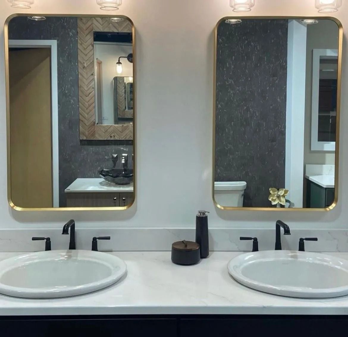 Double bathroom vanity with two round sinks, black faucets, and gold-framed mirrors above a white countertop