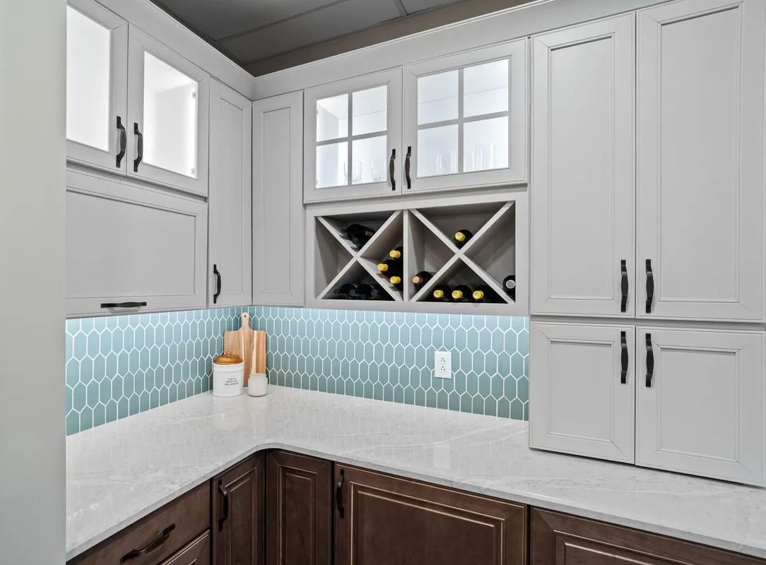 Modern kitchen with white cabinets, gray countertop, blue tile backsplash, and wine rack