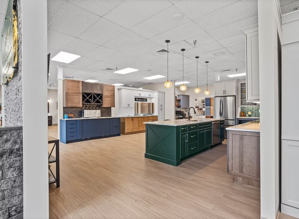 Bright, modern kitchen with blue and green cabinets, island, pendant lights, and wood-look flooring