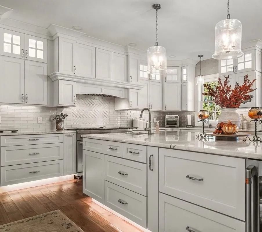 Bright white modern kitchen with island, pendant lights, marble countertops, and hardwood floors