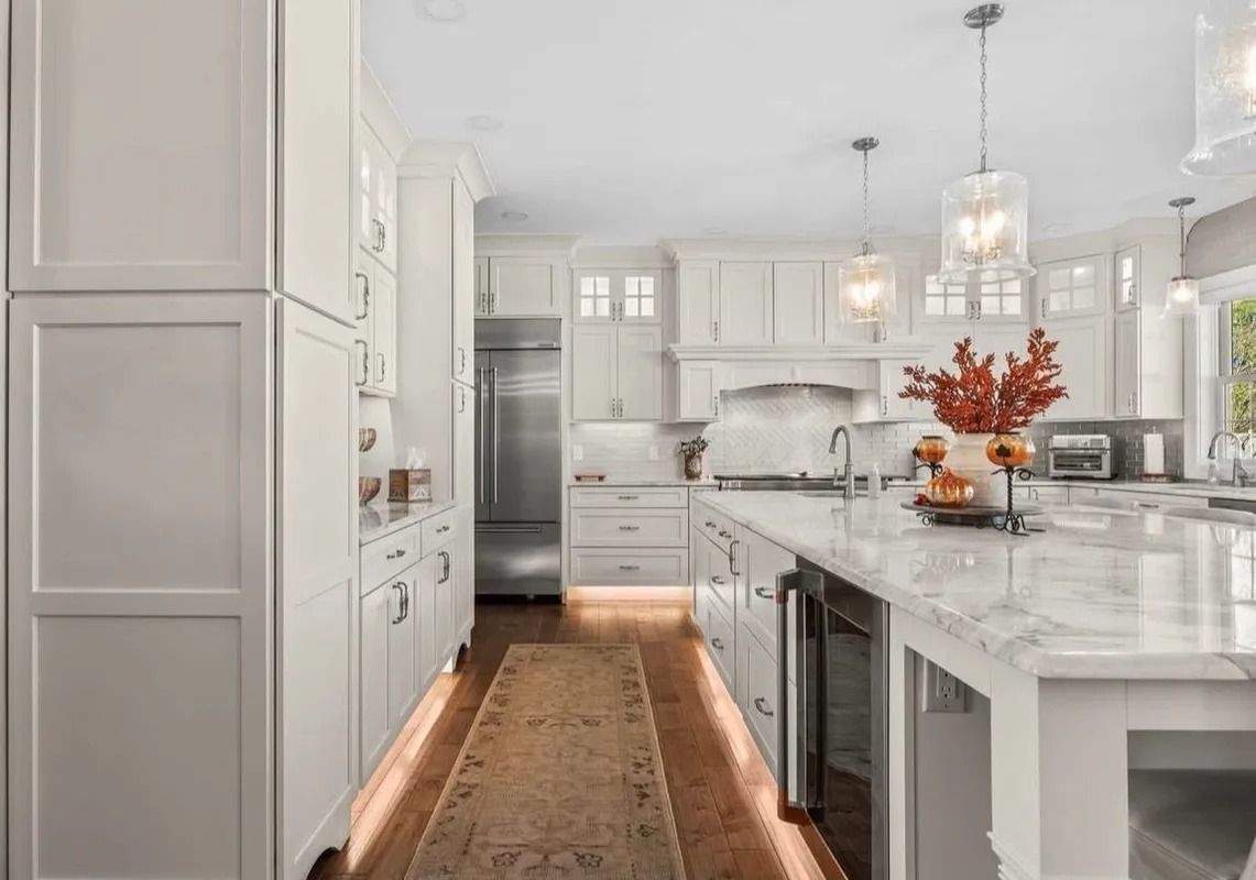 Bright modern white kitchen with marble island, stainless appliances, and a long runner rug