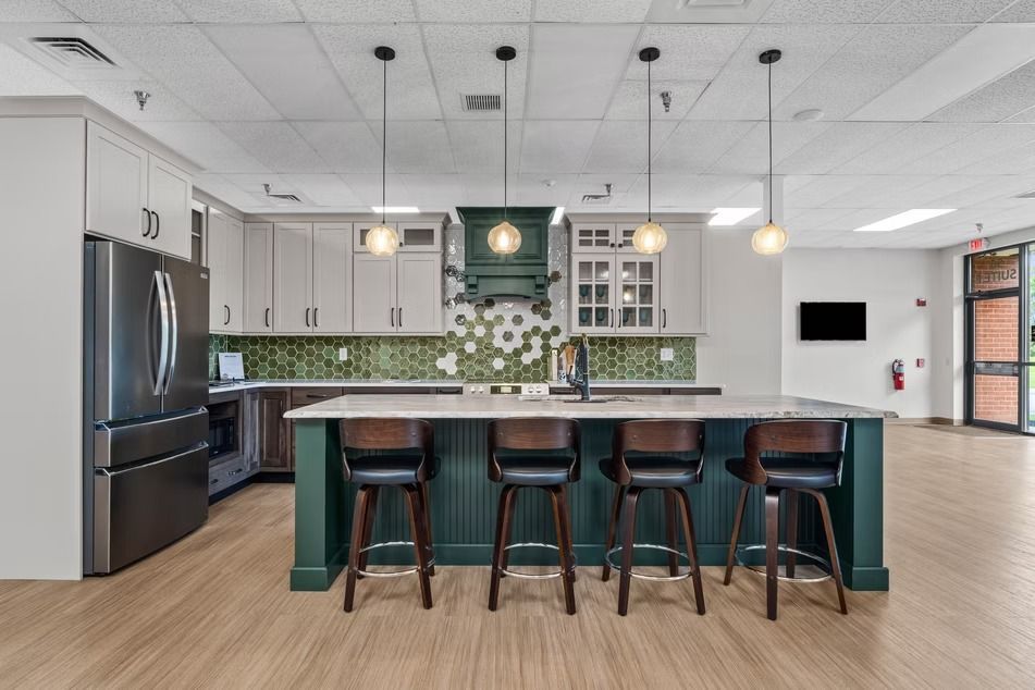 Modern kitchen with green island, bar stools, stainless fridge, and floral backsplash