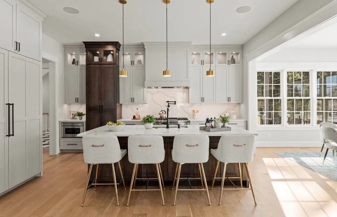 Bright white modern kitchen with island seating, stainless fridge, and sunlit dining area by French doors