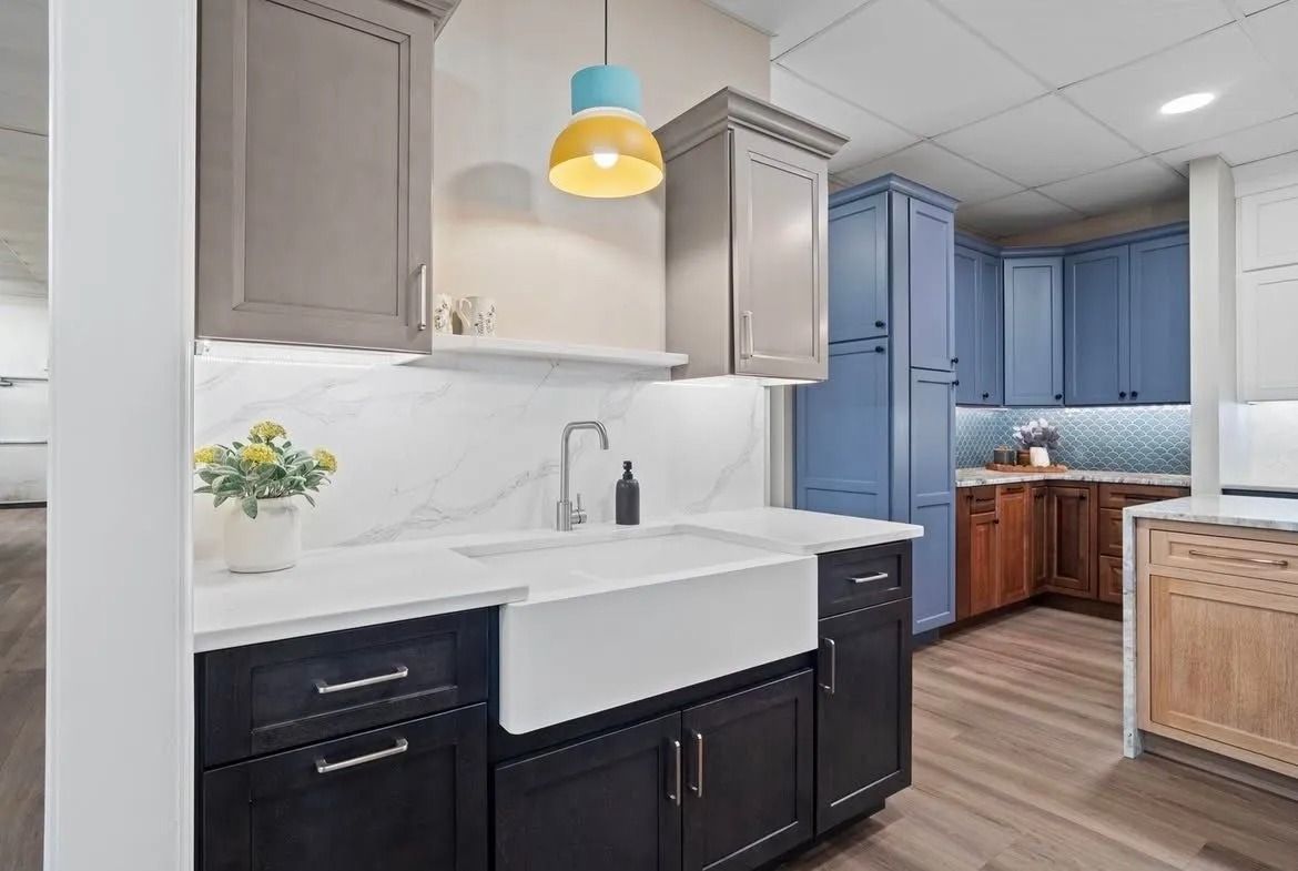 Modern kitchen with white farmhouse sink, dark cabinets, blue island, and yellow pendant light