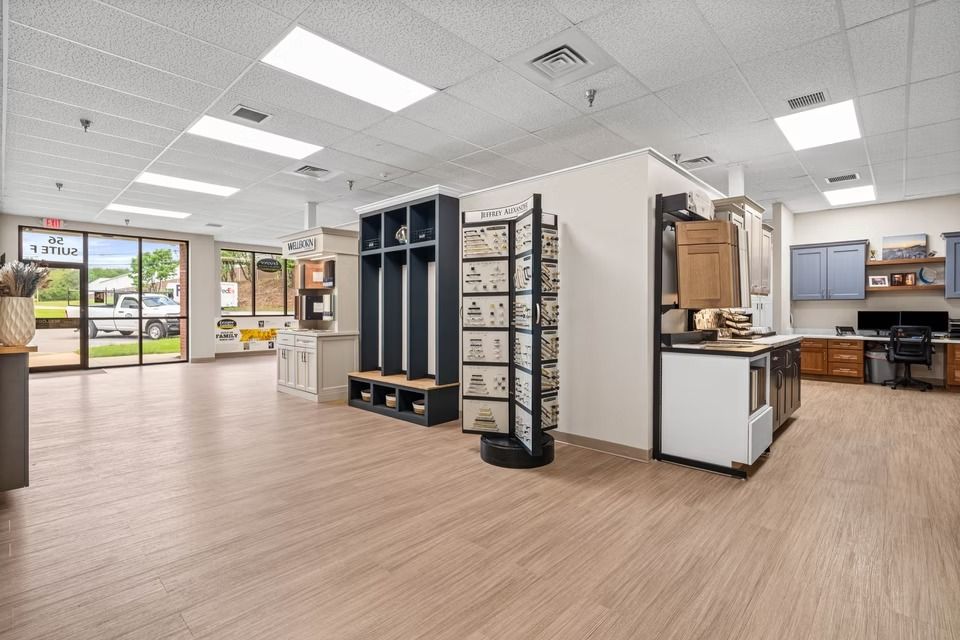 Bright showroom with display fixtures, wood-look floors, and glass storefront doors under fluorescent lights