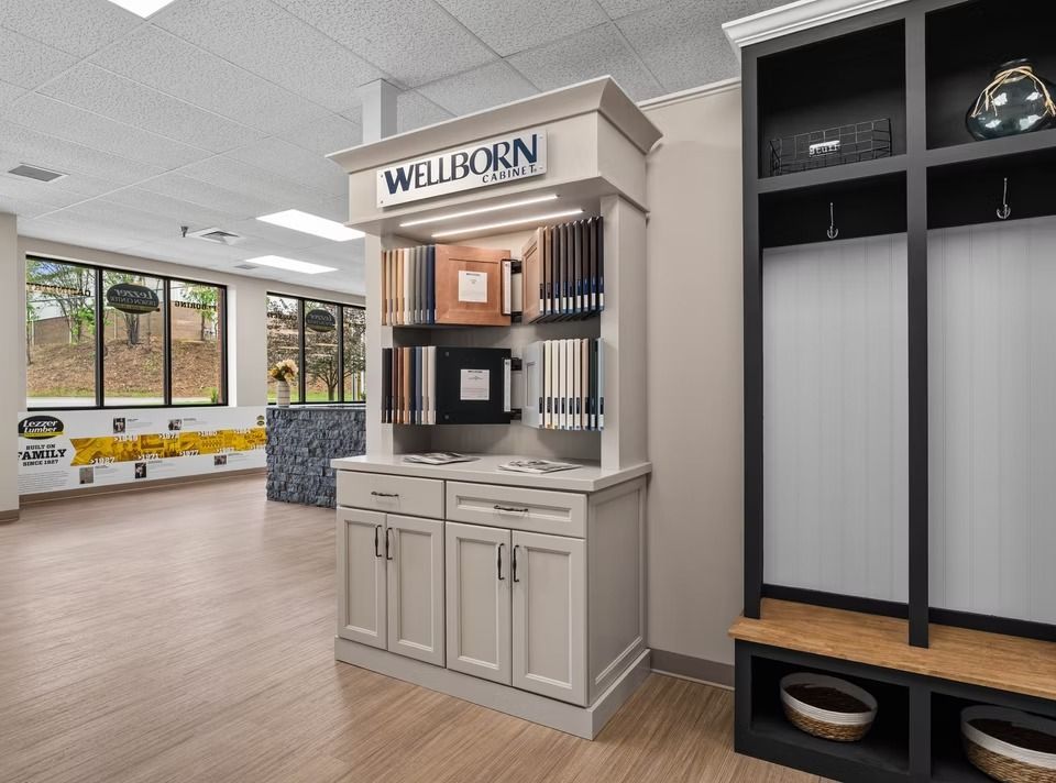 WELLBORN cabinetry display in a showroom, with light gray cabinets, shelves, and a wine fridge against a beige wall