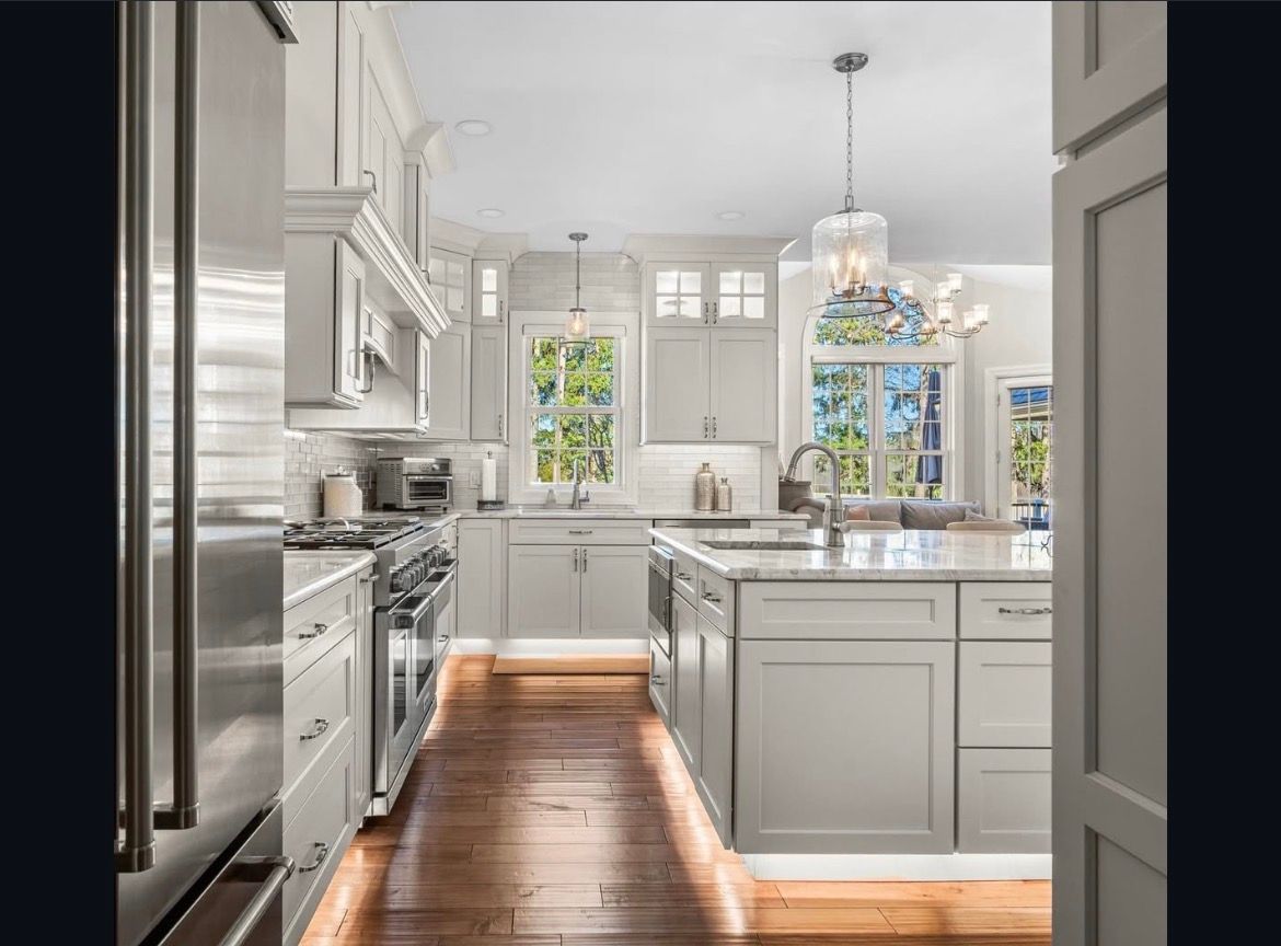 Bright white kitchen with island, pendant lights, and sunlight on hardwood floors