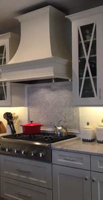 Modern kitchen with white cabinets, stovetop, red pot, and glass-front pantry door