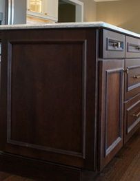 Dark wood kitchen island cabinet with white stone countertop and decorative trim