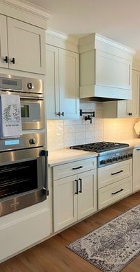 Modern white kitchen with built-in stainless oven, gas range, and cream cabinets