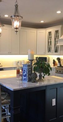 Modern kitchen with white cabinets, dark island, hanging pendant light, and potted plants on the countertop