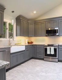 Modern gray kitchen with white countertops, stainless steel appliances, and a window over the sink